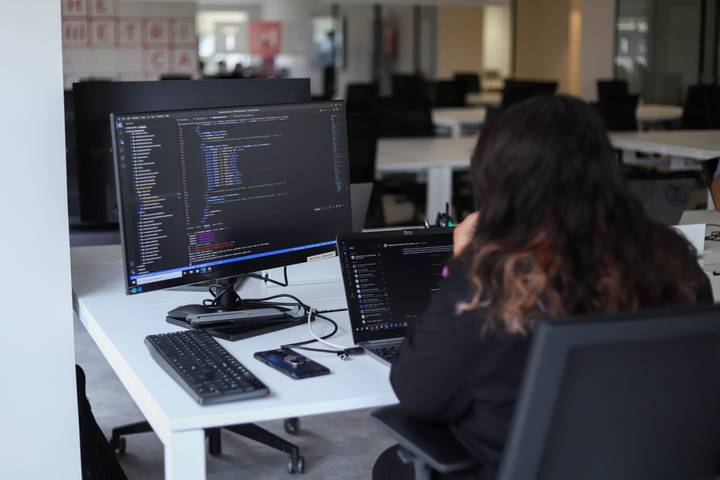 Developer working with code on a monitor and a laptop