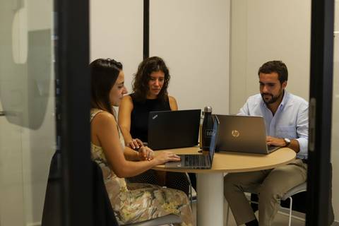 Equipo de METRICA trabajando con portátiles en una mesa de reuniones